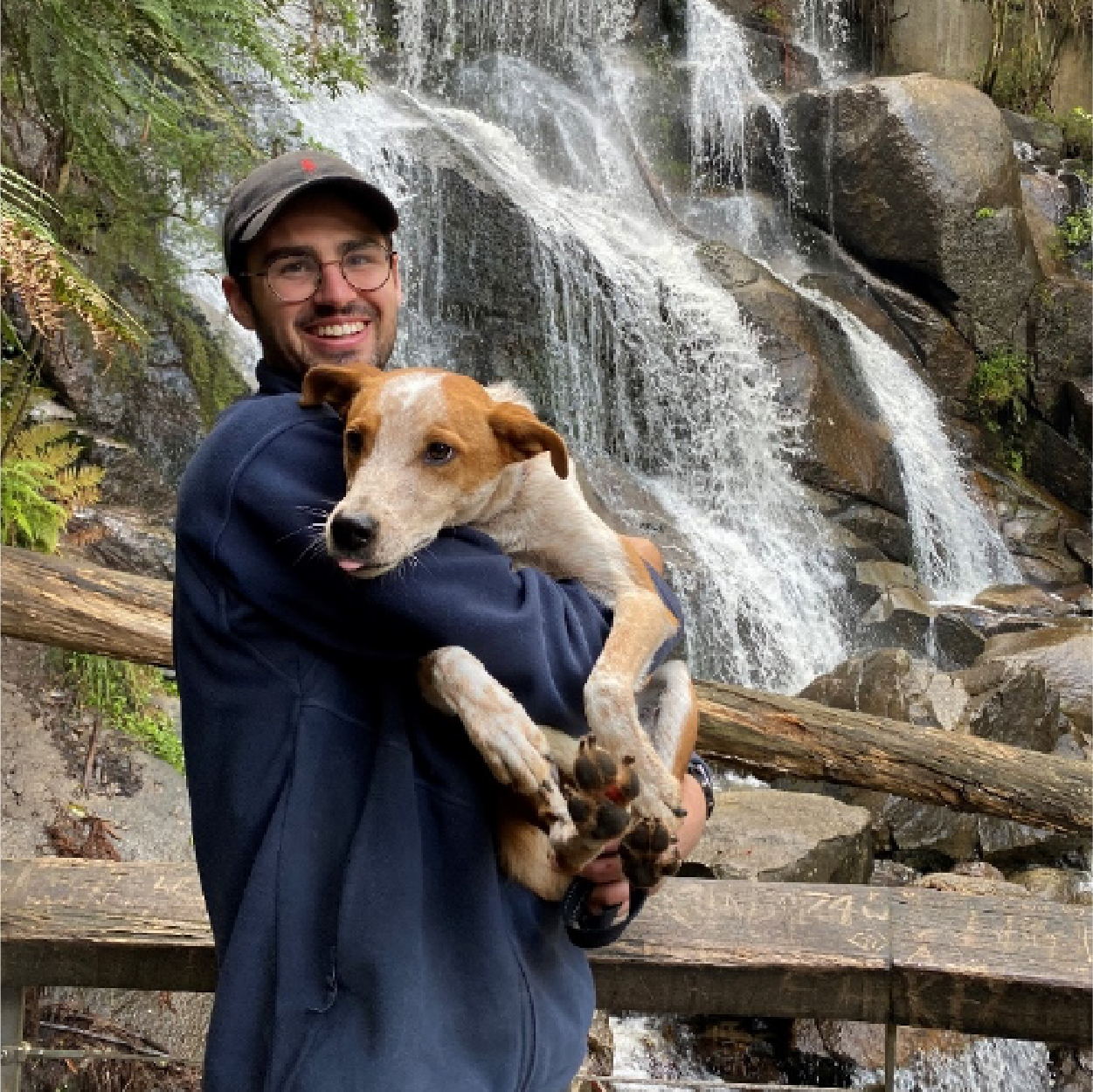 PARC Swim teacher Lachlan holding his dog in front of a waterfall